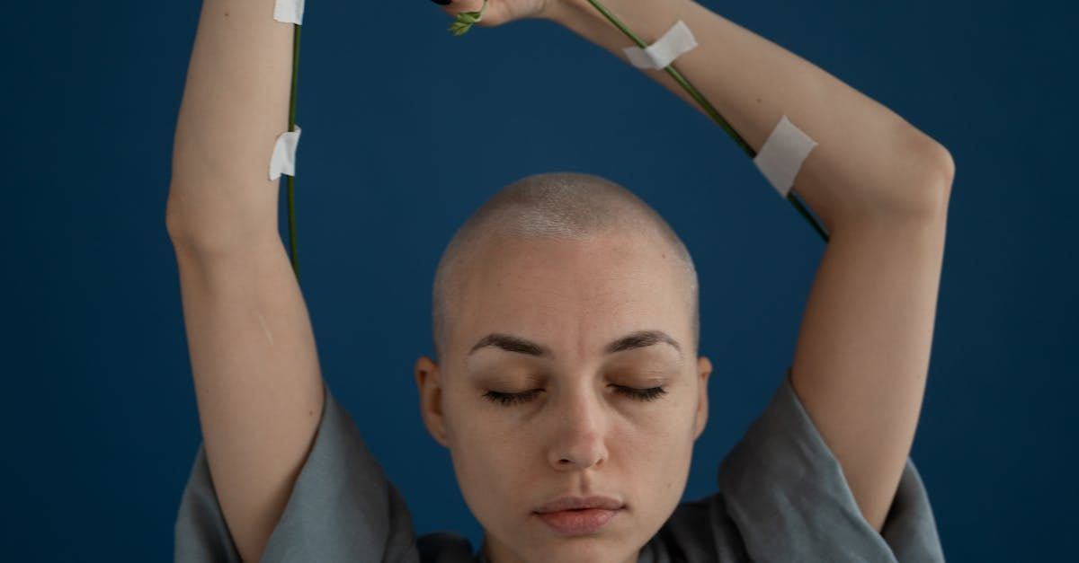 A woman with a bald head is holding a flower in her hands.