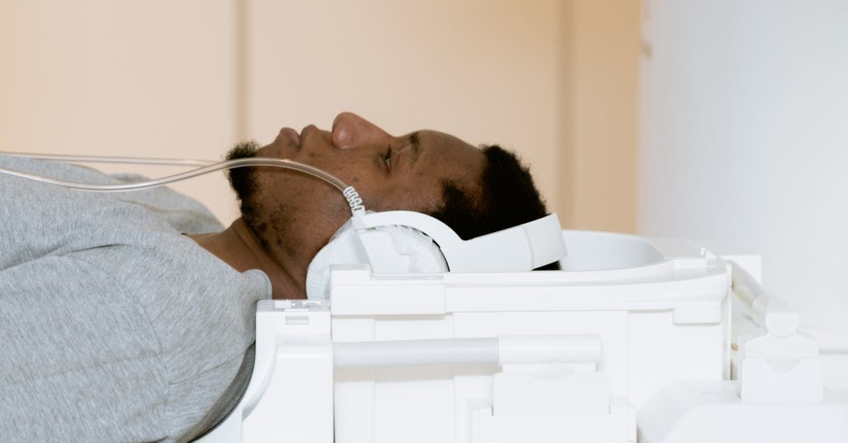 A man is laying in a hospital bed with headphones on his head.