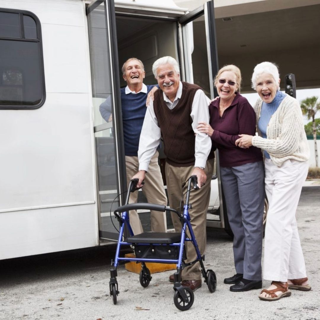 A group of elderly people are posing for a picture in front of a bus