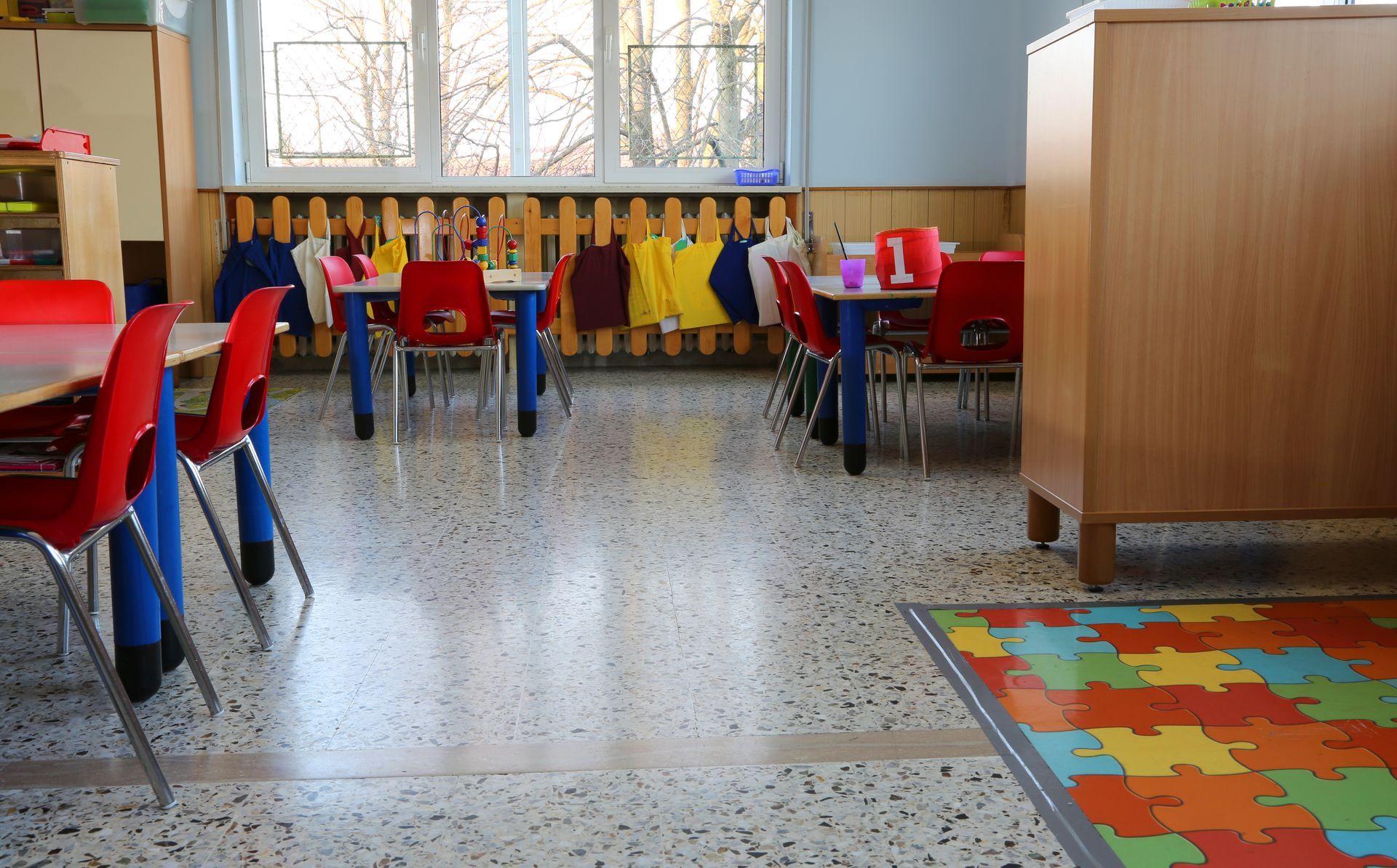 Une salle de classe avec des tables, des chaises et un tapis puzzle