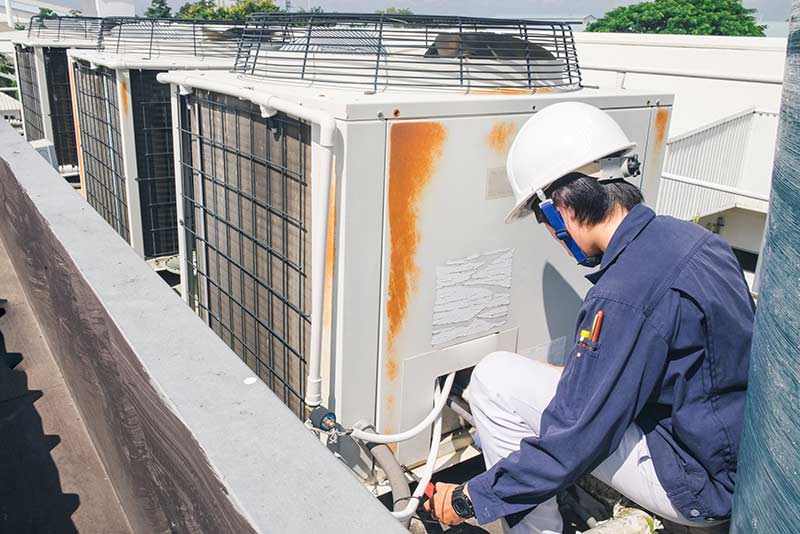 Boiler Installation — Man On The Top Of The Building Checking The Water System in Church Road