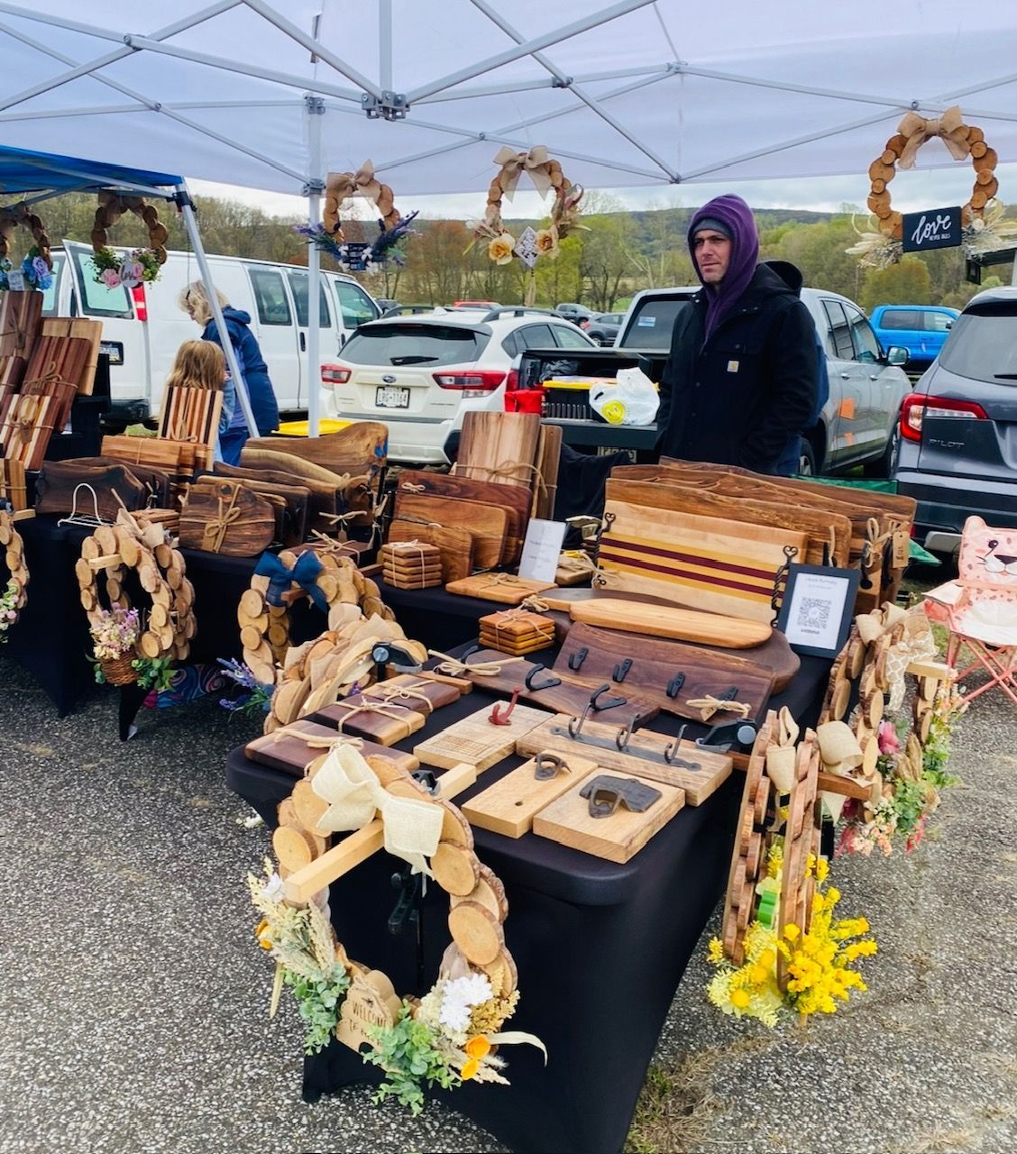 A man stands behind a table full of wooden items