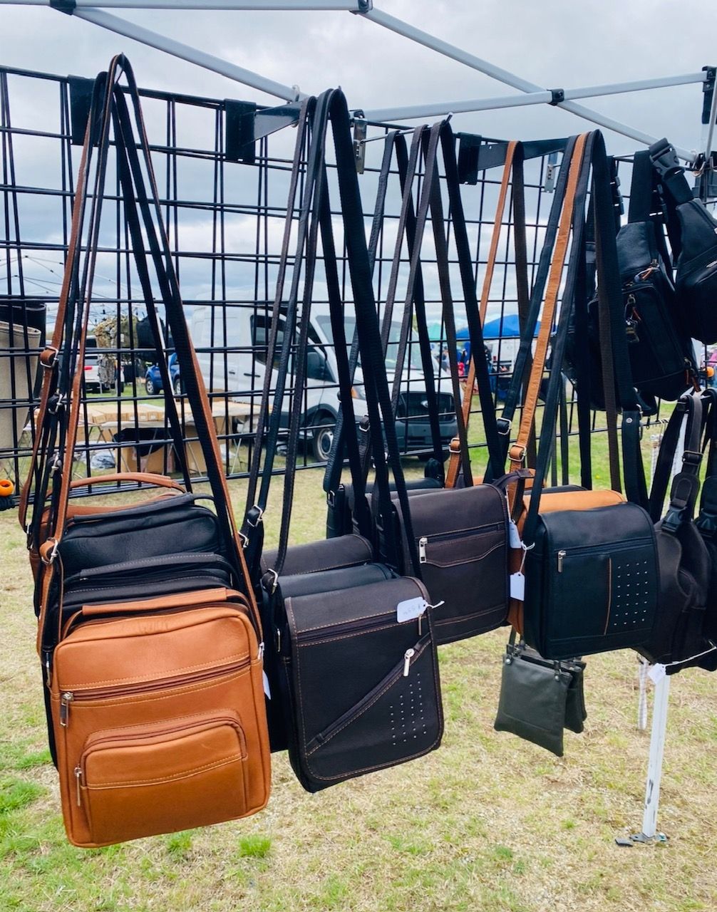 A bunch of bags are hanging from a fence in a field.