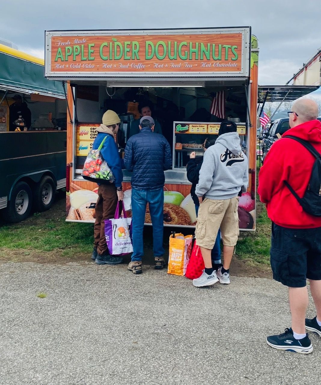 People standing outside of an apple cider doughnut stand