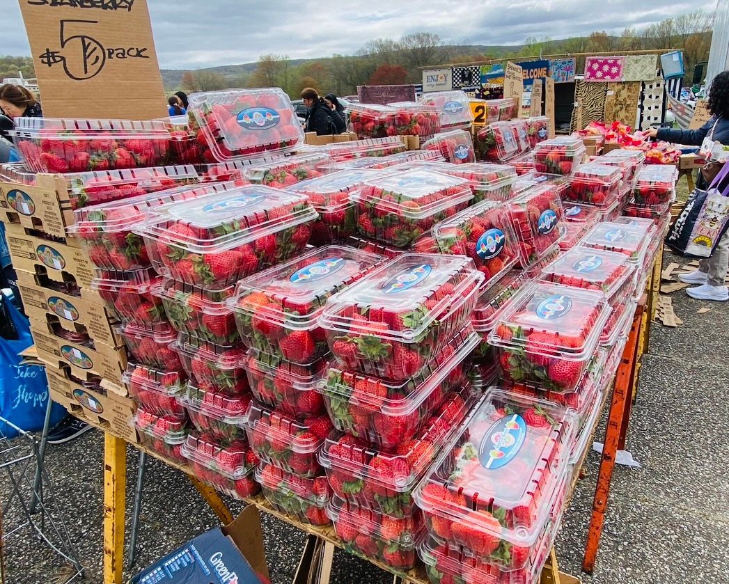 A bunch of plastic containers of strawberries are stacked on top of each other on a table.