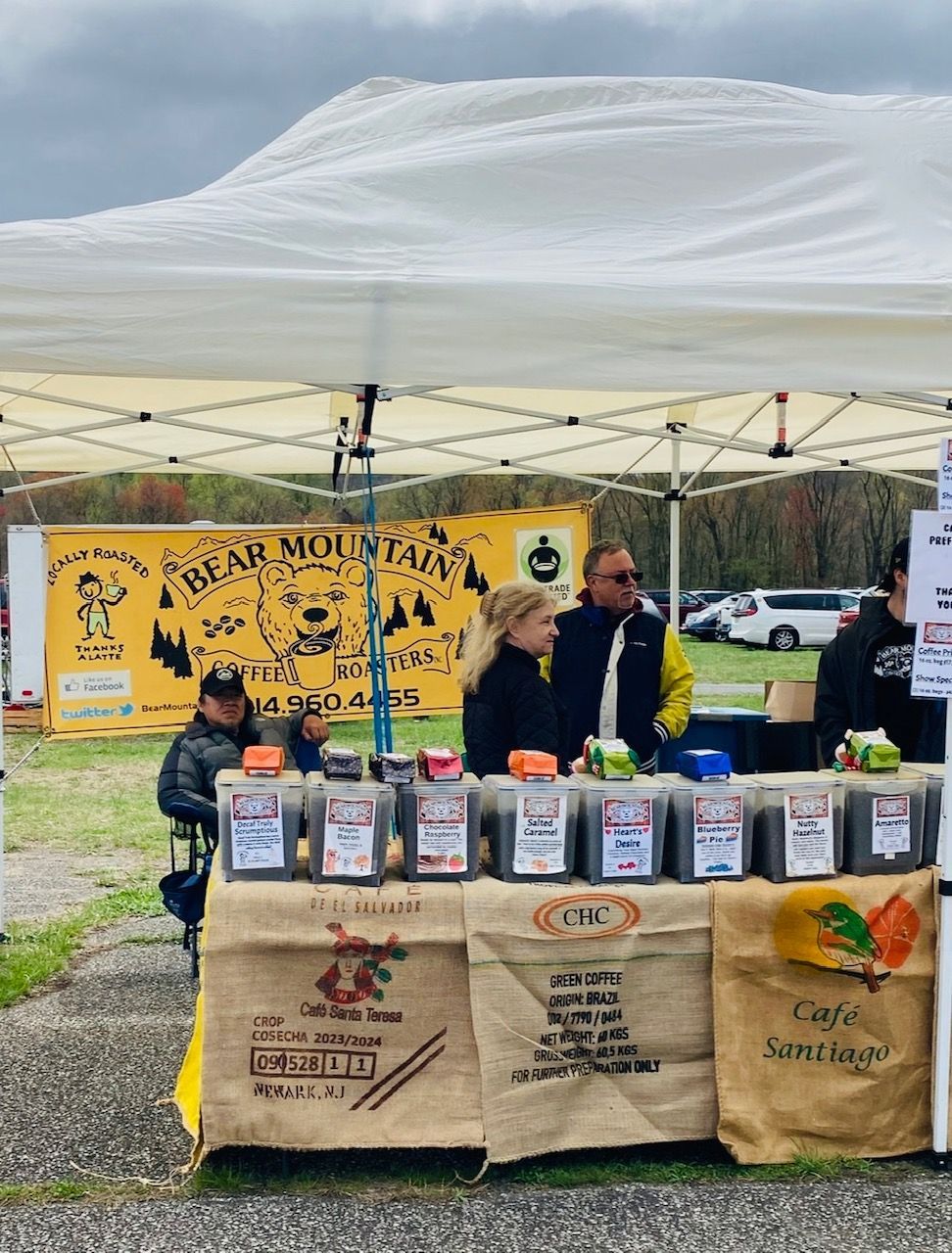 A group of people standing around a table under a tent that says bear mountain farms