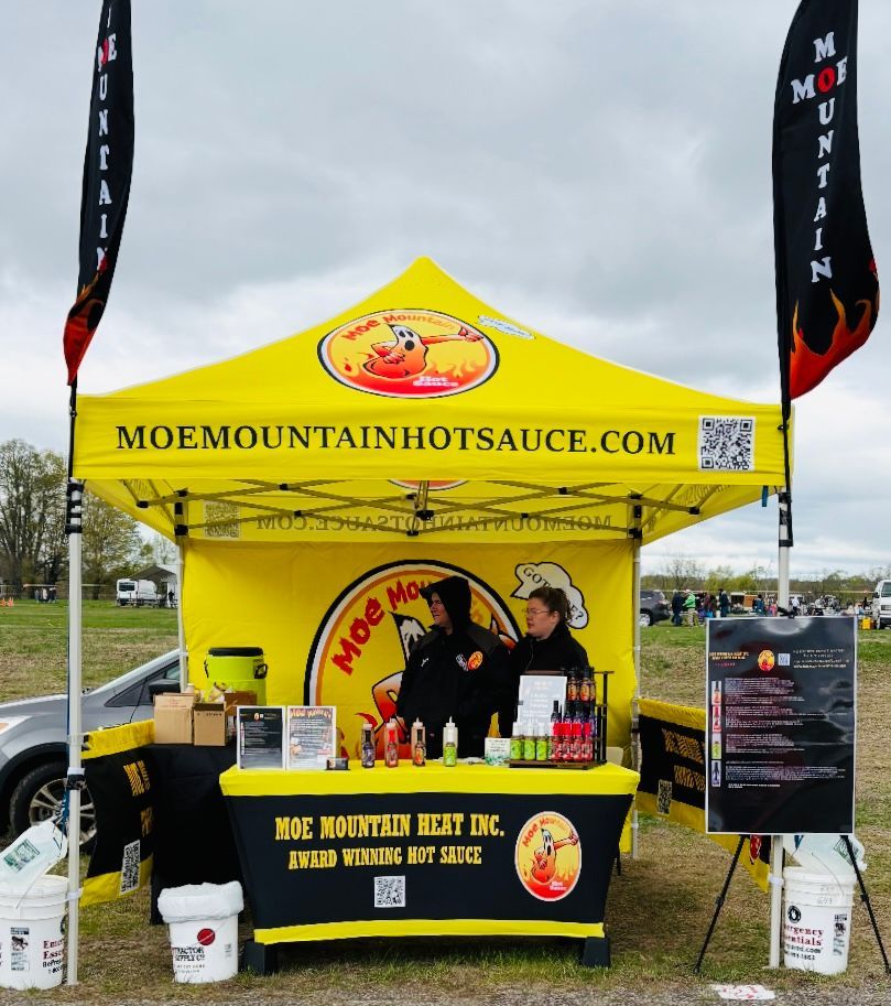 A yellow tent with the website moemountainhotsauce.com on it
