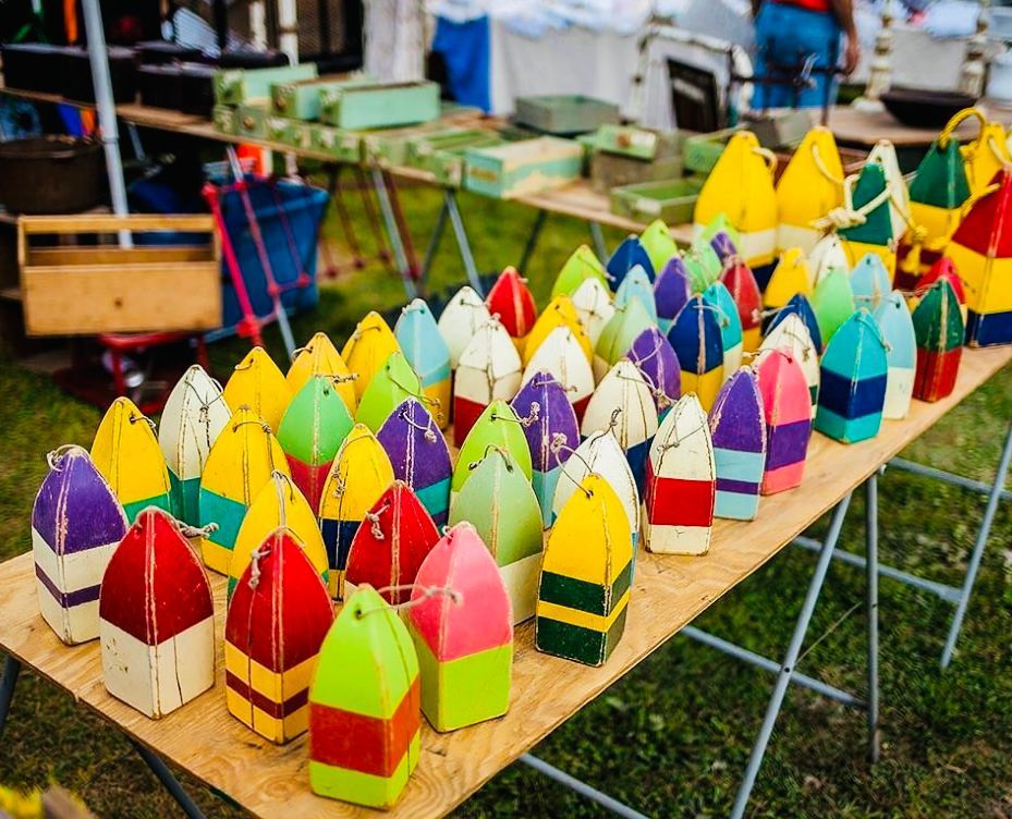 Colorful, striped buoys arranged on a table at an outdoor market.