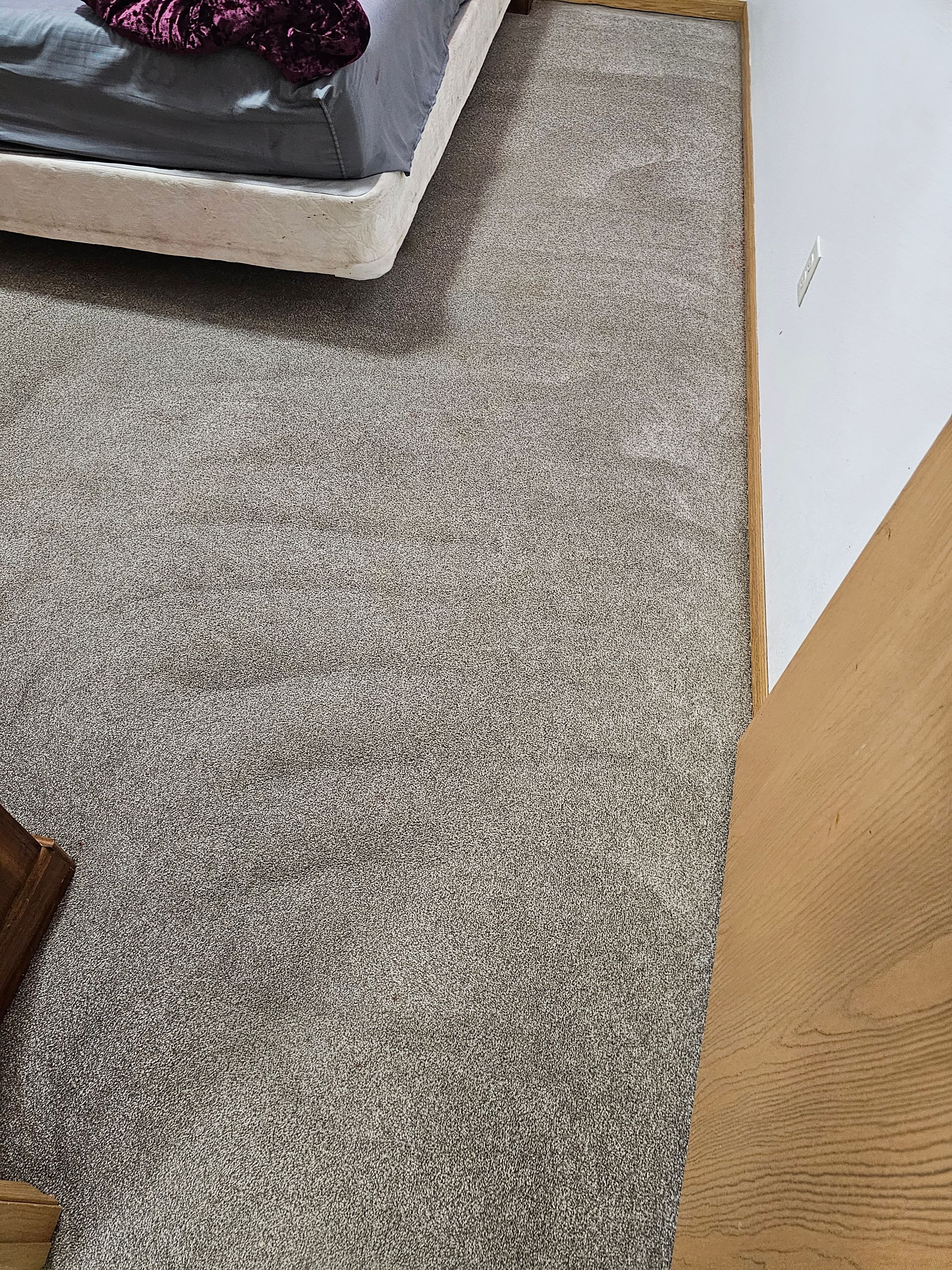 A bedroom with a bed and a rug on the floor.