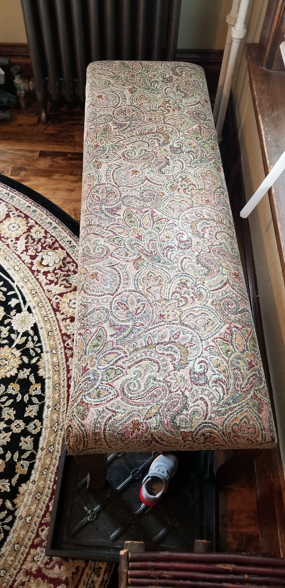 A bench is sitting on a wooden floor next to a rug.