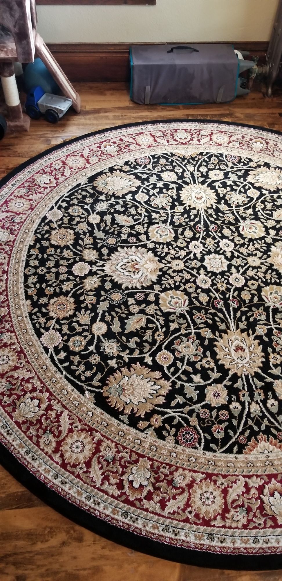 A round rug is sitting on a wooden floor in a living room.