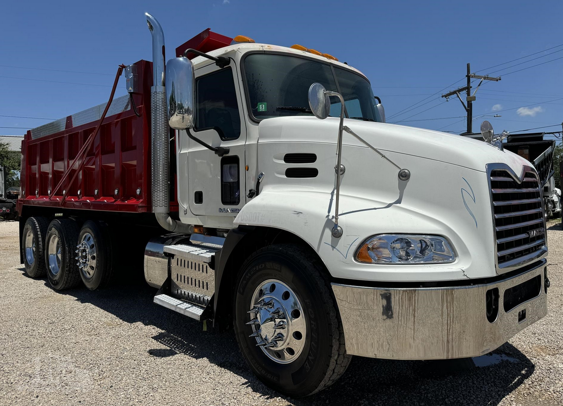 White and red dump truck parked under a blue sky. Chrome details and shiny wheels are visible.