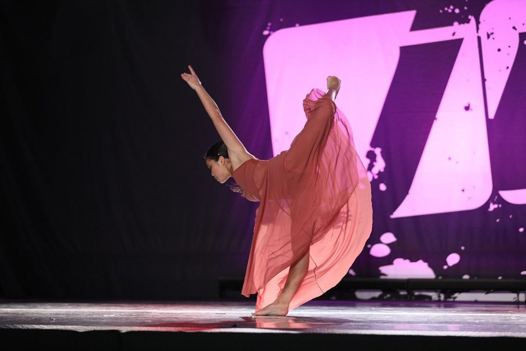 A woman in a pink dress is dancing on a stage.