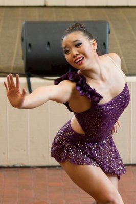 A woman in a purple dress is dancing in front of a speaker.