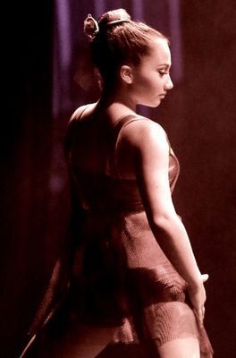 A woman in a red dress is standing in a dark room.