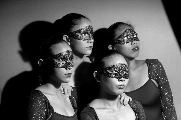 Four women wearing masks are standing next to each other