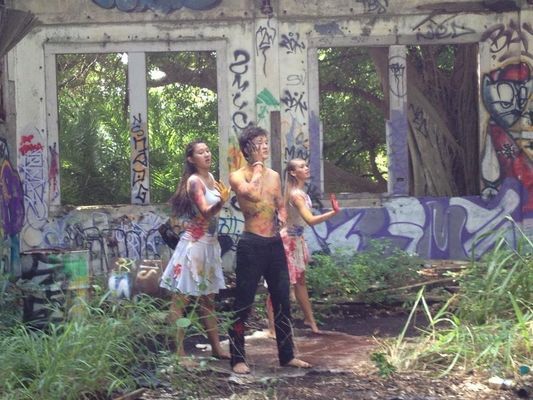 A group of people are standing in front of an abandoned building covered in graffiti.