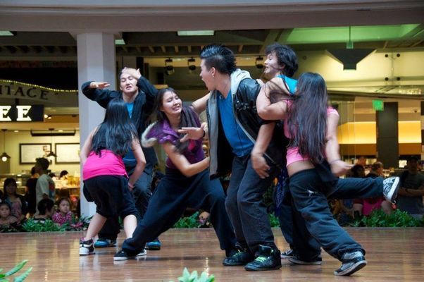 A group of people are dancing on a stage in front of a sign that says peace