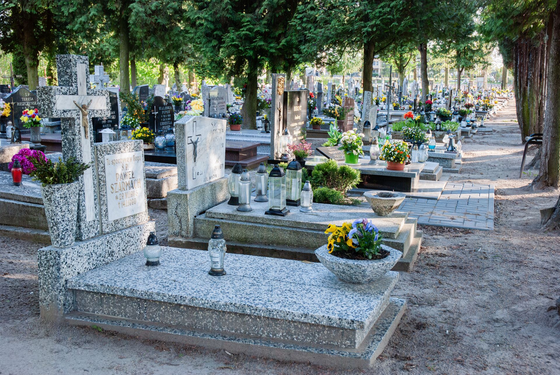 Peaceful cemetery with granite monuments and colorful flowers amidst tall trees. Peaceful cemetery with granite monuments and colorful flowers amidst tall trees.