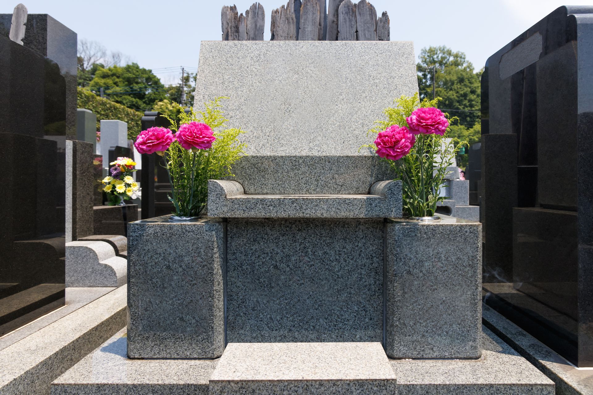 A large granite monument with pink flowers placed on custom placeholders. A large granite monument with pink flowers placed on custom placeholders.