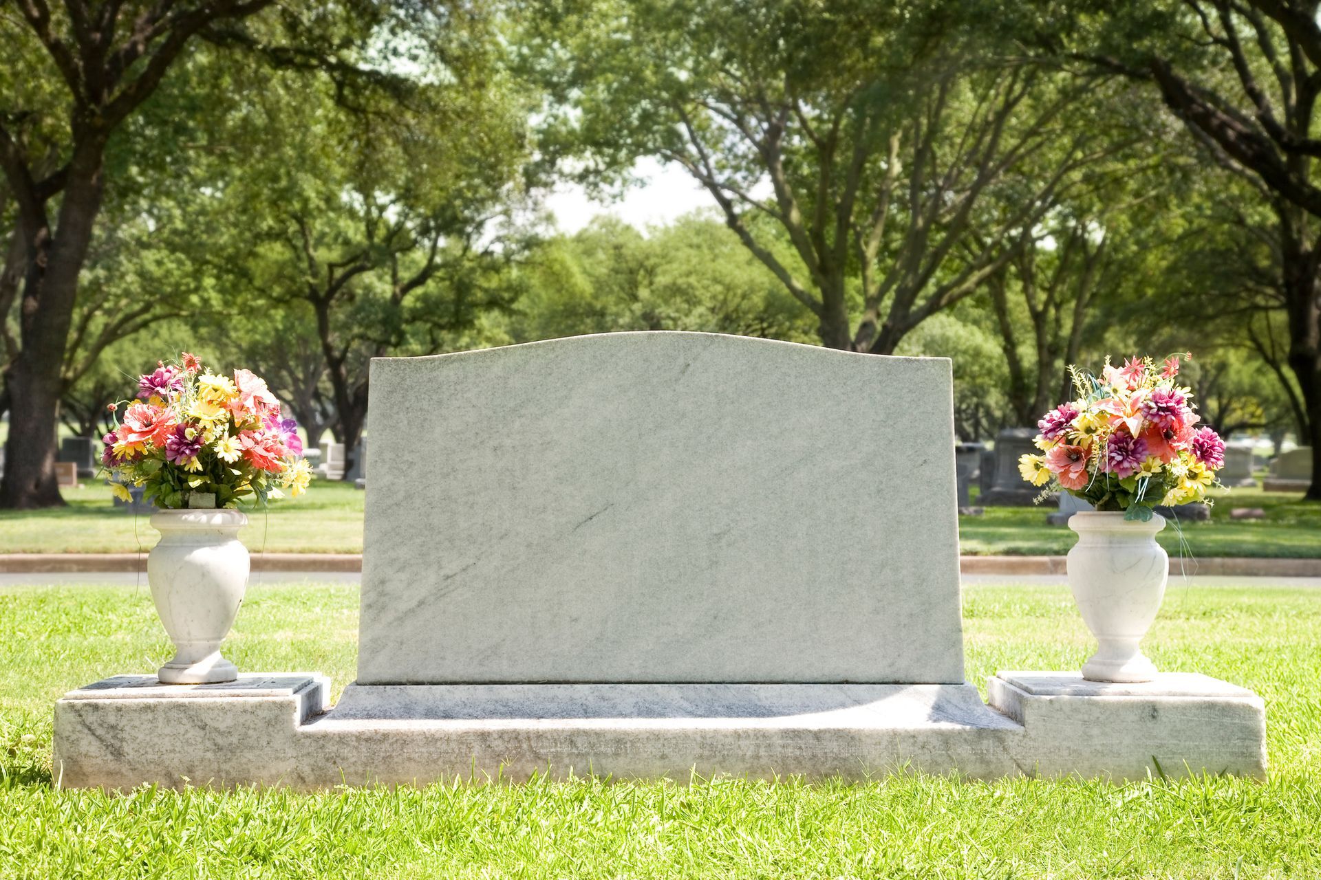 Elegant custom monument tombstone with vibrant flowers at a quiet cemetery, perfect memorial.