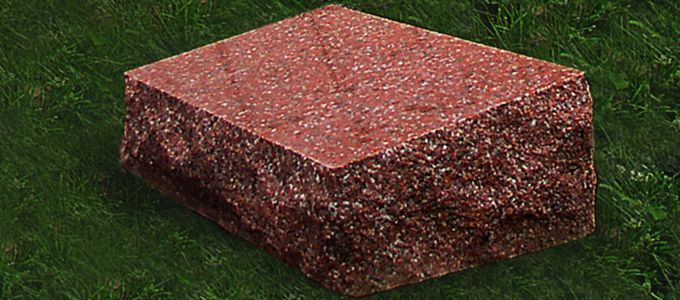 A red, textured brick sits on green grass.