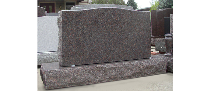 A gravestone is sitting on top of a concrete slab.