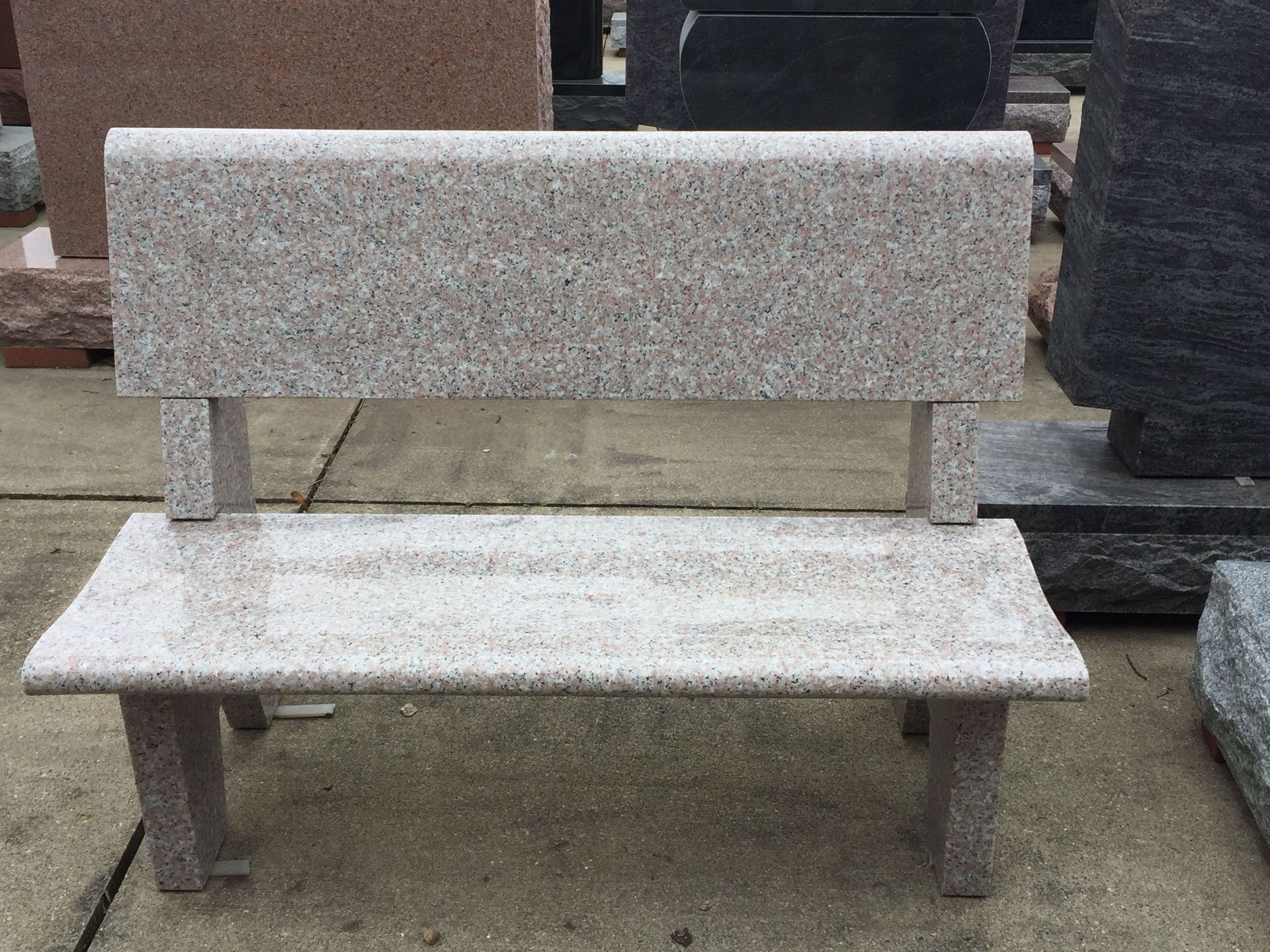 Granite bench with a back, likely outdoors, light speckled color.