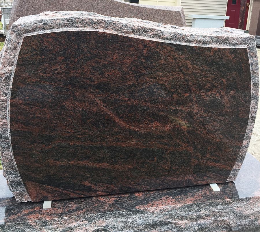 A red and black granite headstone with a curved central panel.