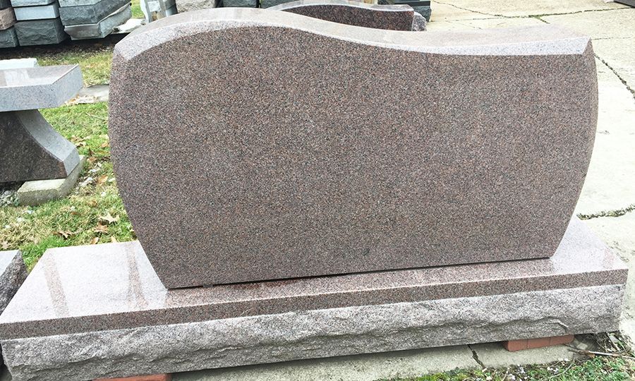 Brown granite headstone with curved top and base.