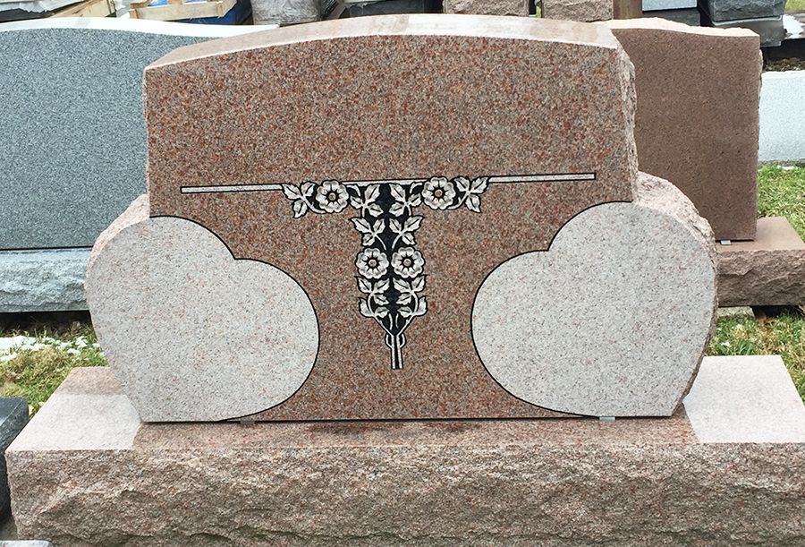 Pink granite headstone with two heart-shaped sections and floral design.