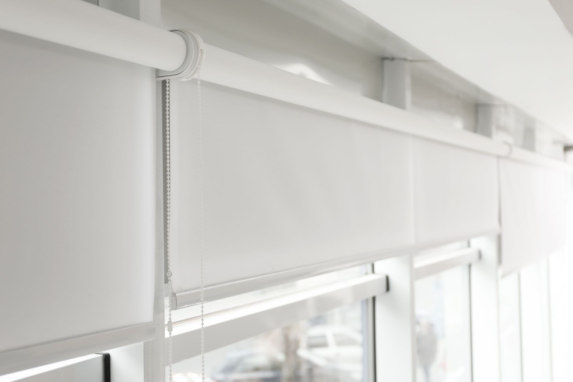 A close up of a white roller blind on a window.