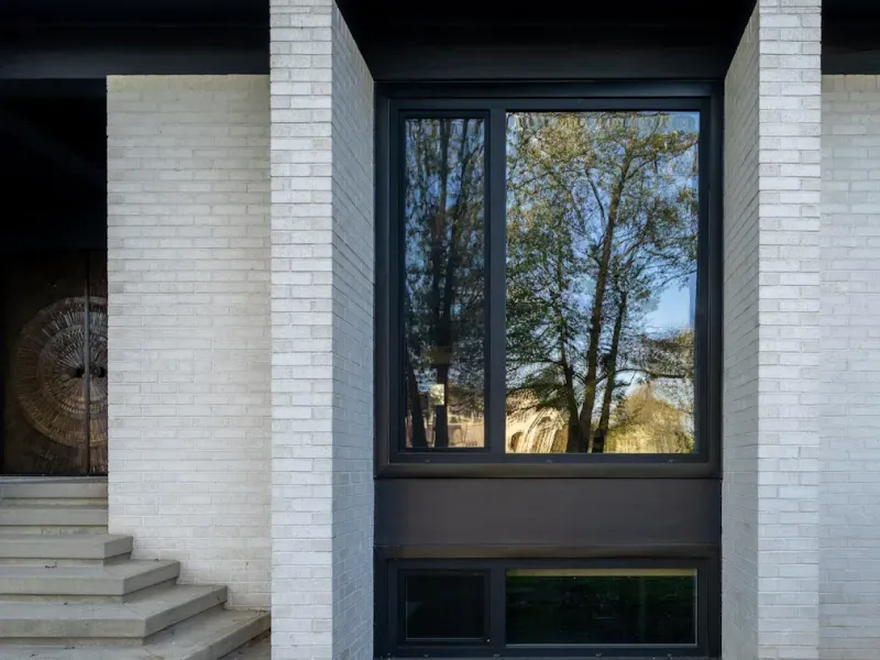 A white brick building with a large window and stairs.