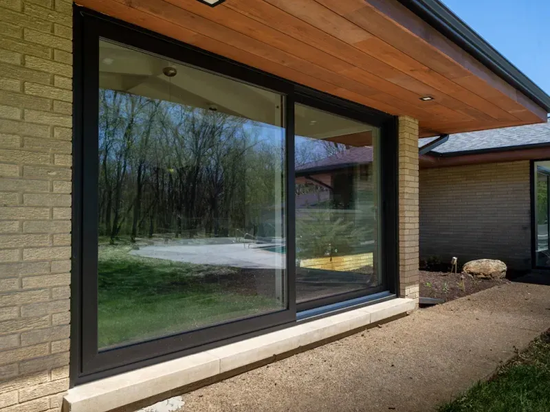 A large sliding glass door is on the side of a brick house.
