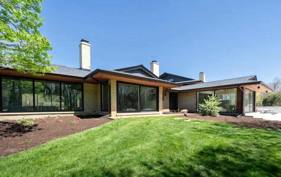 A large house with a lot of windows and a lush green lawn in front of it.