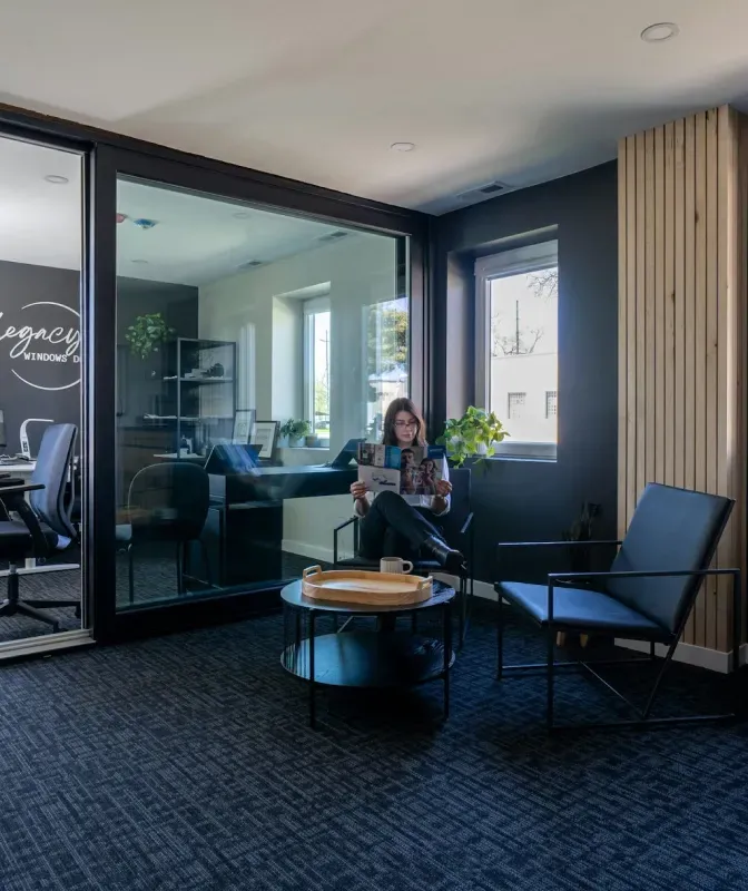A woman is sitting in a chair reading a magazine