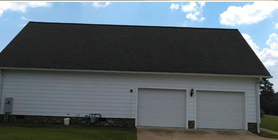 A white garage with two garage doors and a black roof
