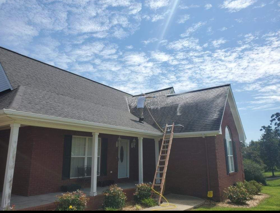A ladder is sitting on the roof of a brick house.