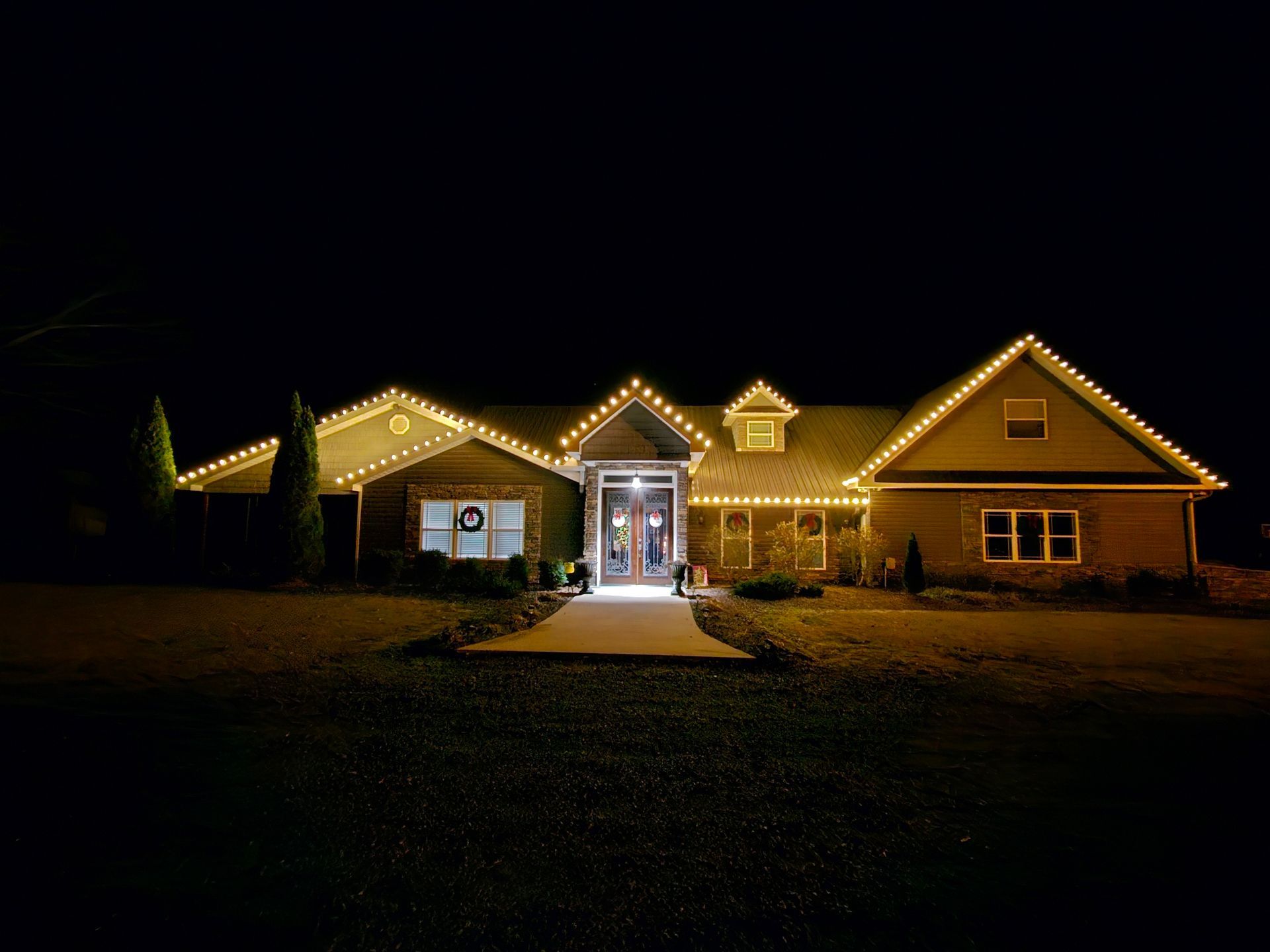 A large house is lit up with christmas lights at night.