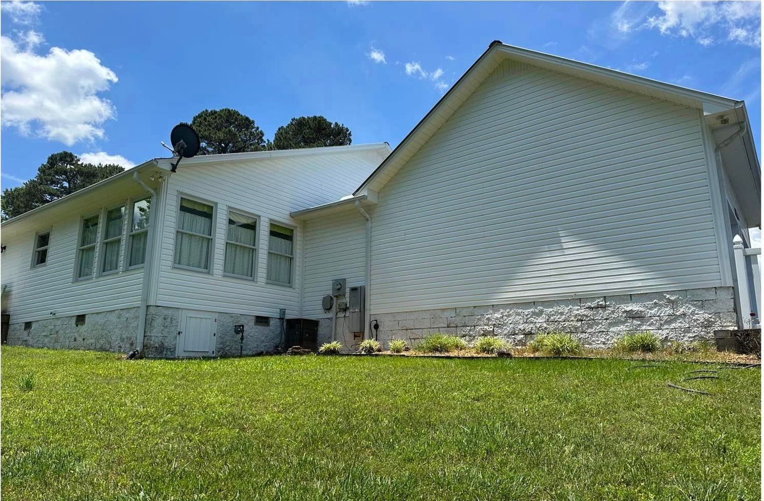 A large white house is sitting on top of a lush green lawn.