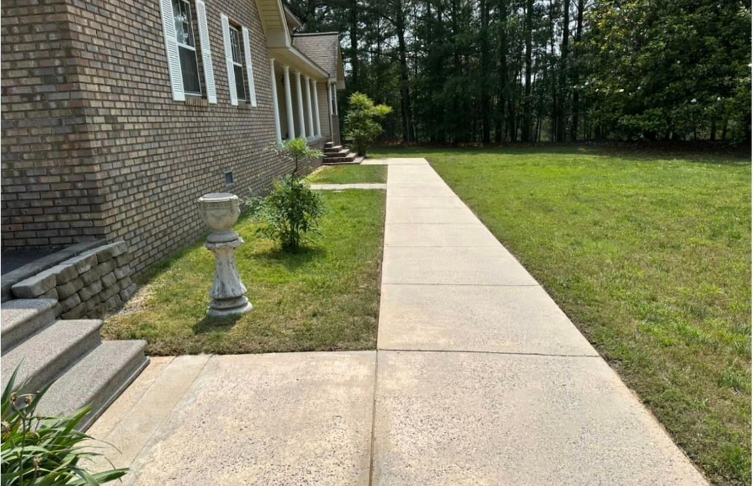 A brick house with a concrete walkway leading to it.