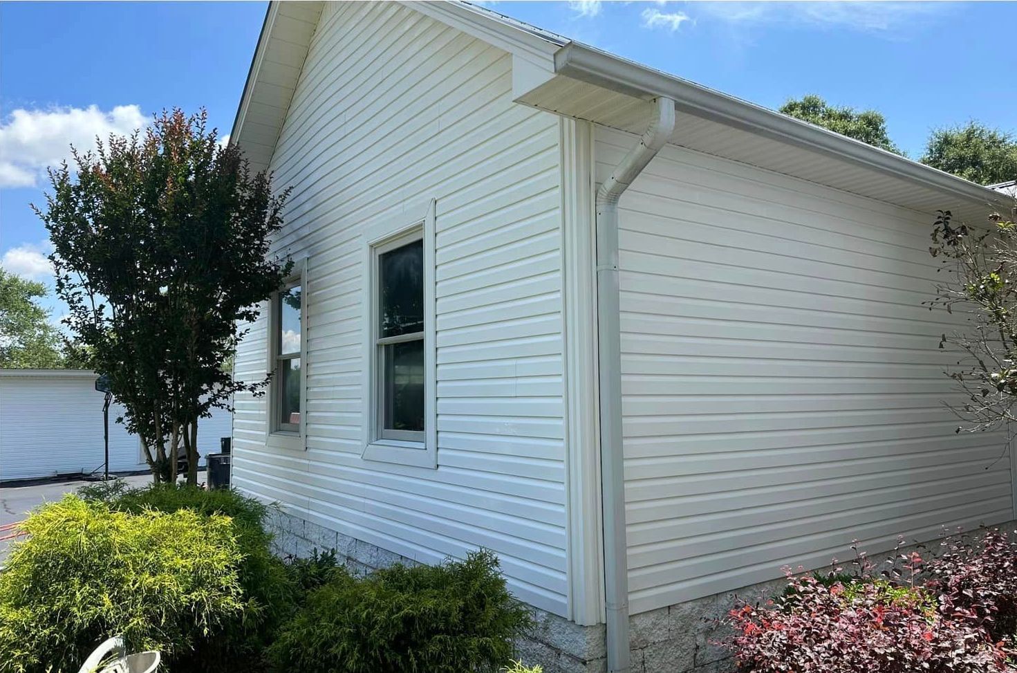 The side of a white house with a window and a gutter.