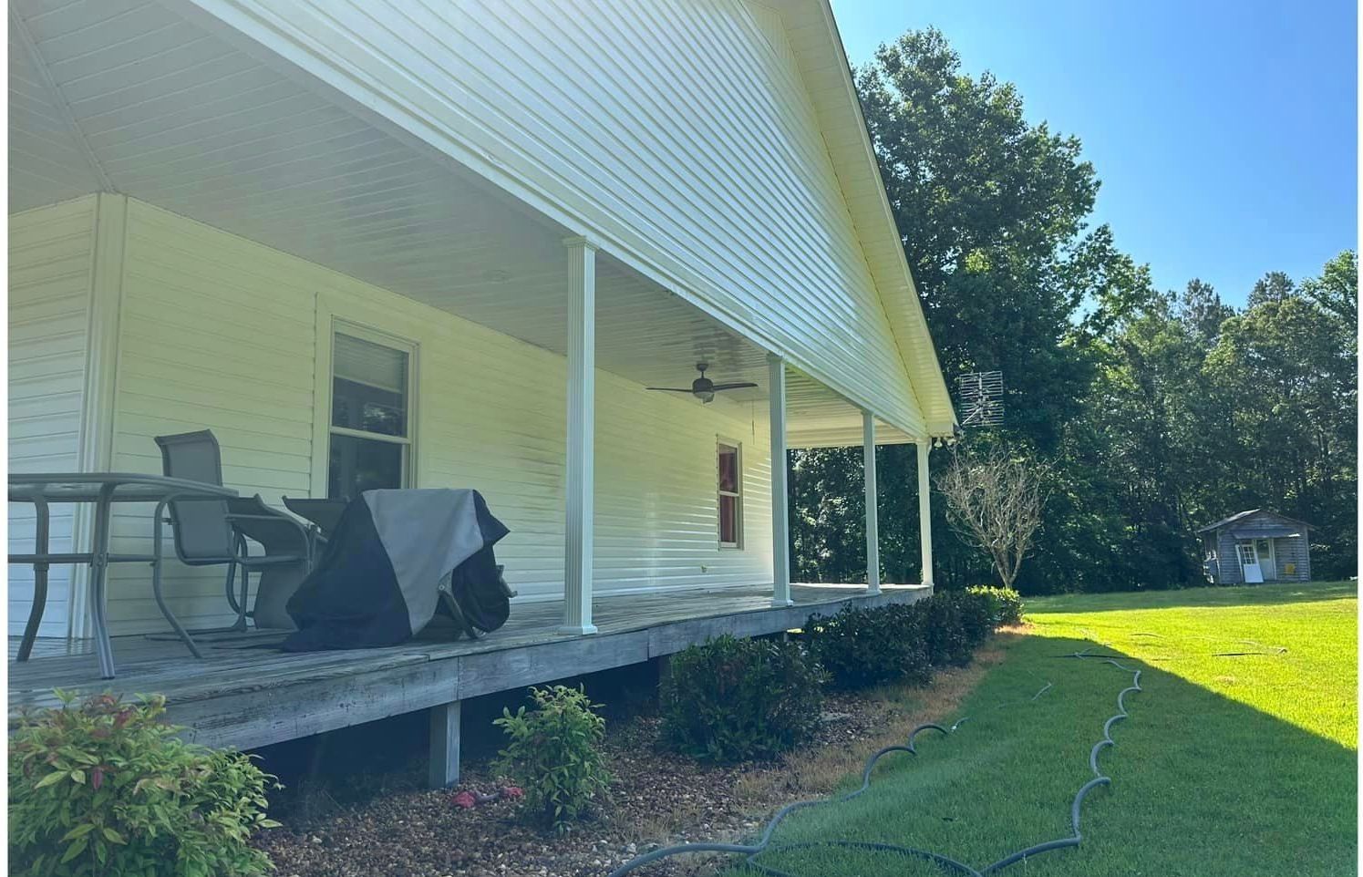 A white house with a porch and a table and chairs on it.