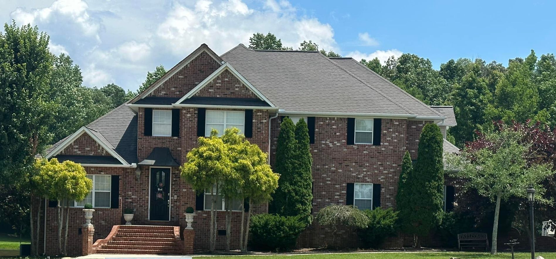 A large brick house with a black roof and black shutters