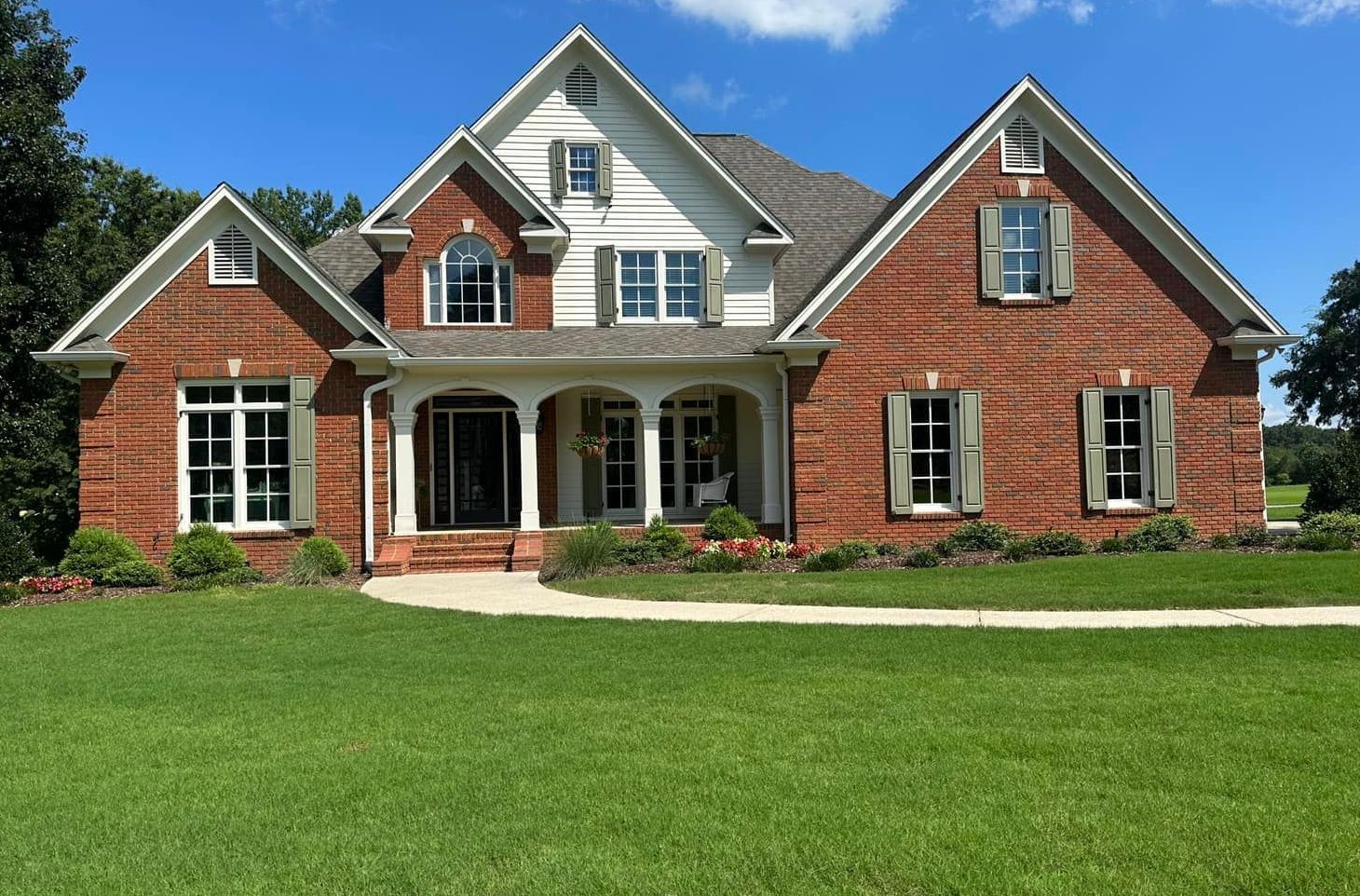 A large brick house with a lush green lawn in front of it