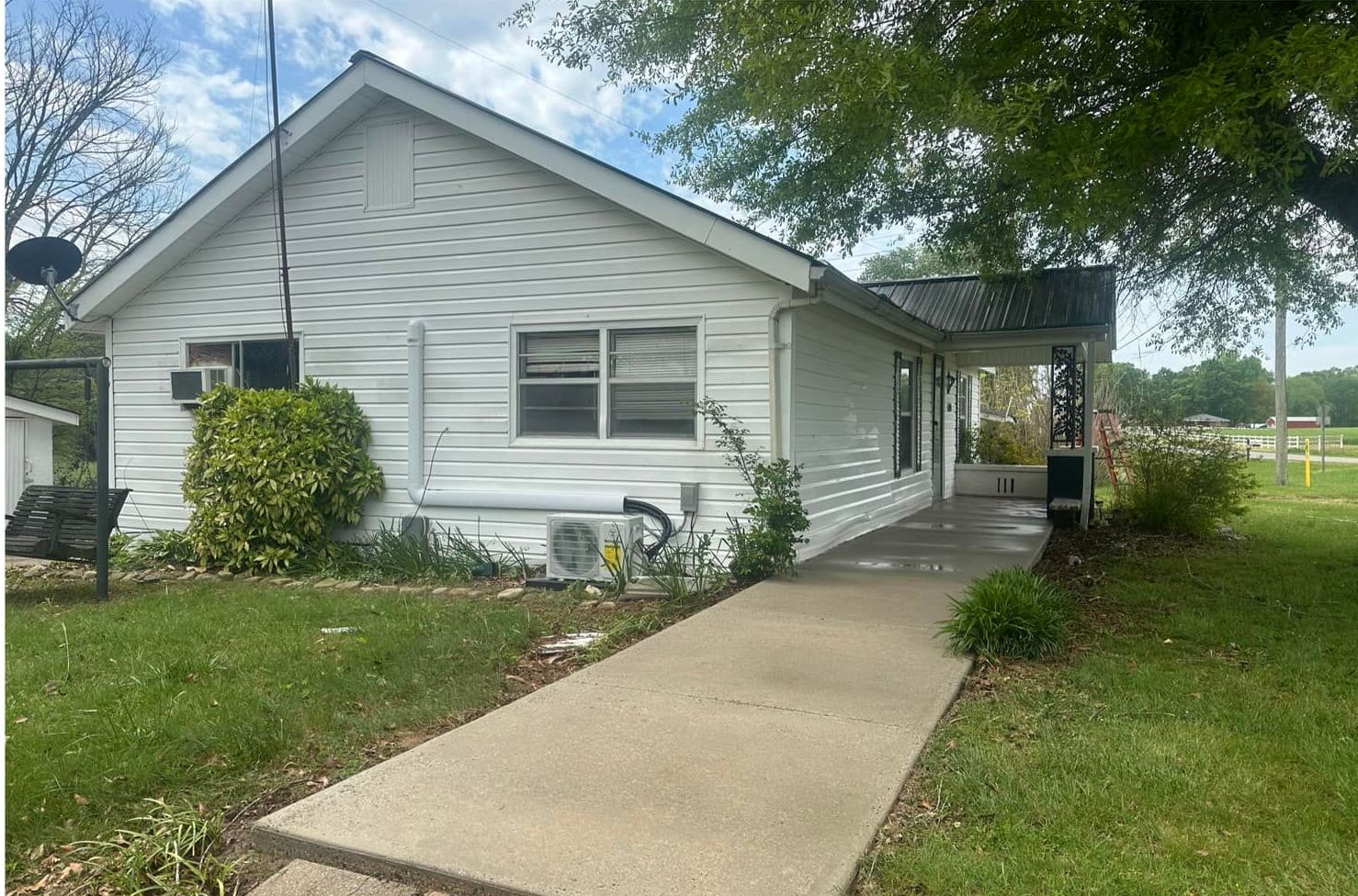 A white house with a concrete walkway leading to it.