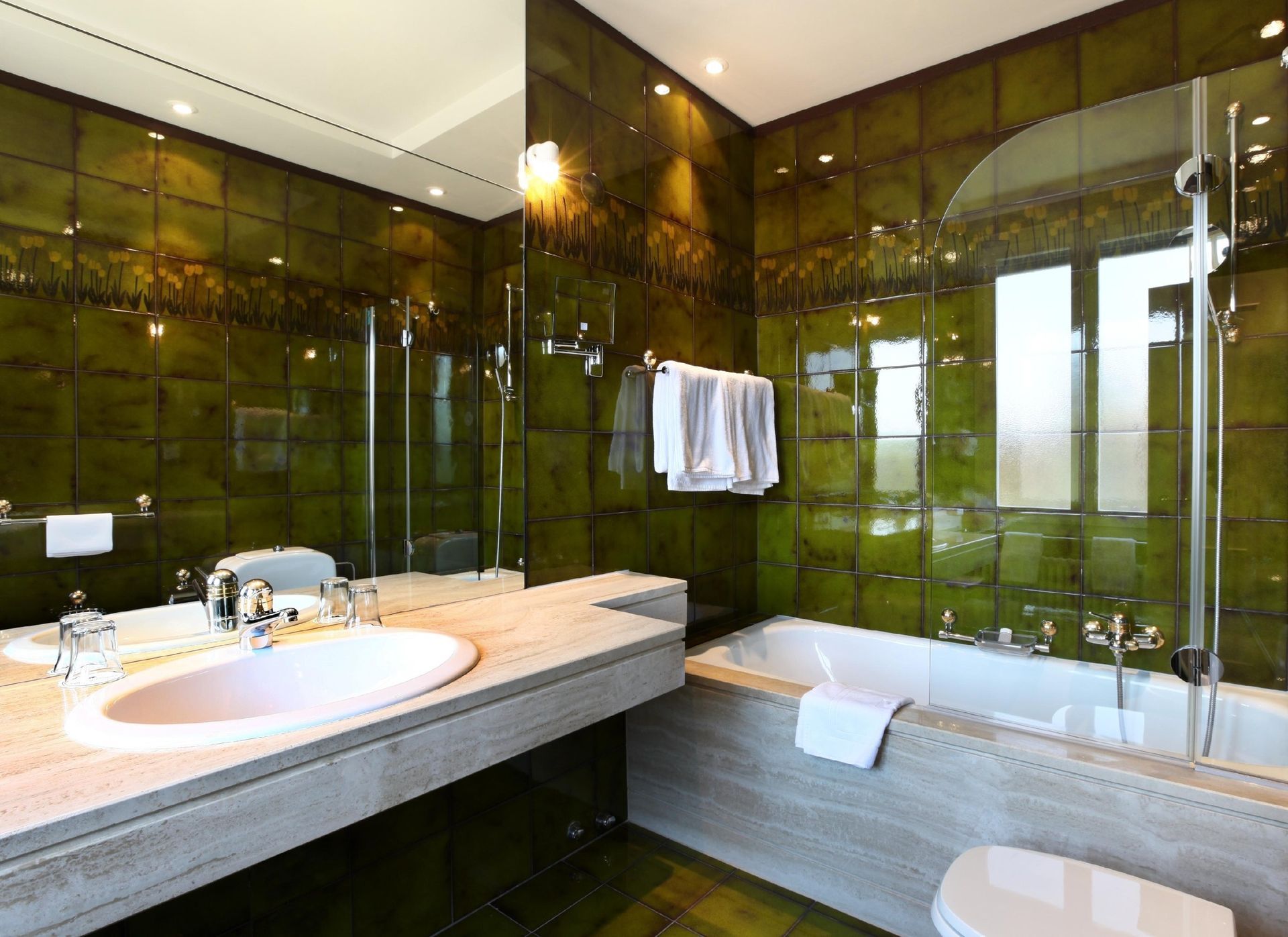 A bathroom with green tiles and a bathtub