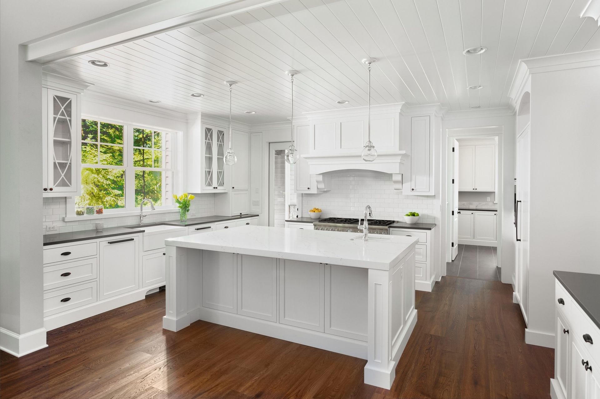 A kitchen with white cabinets and hardwood floors and a large island in the middle.
