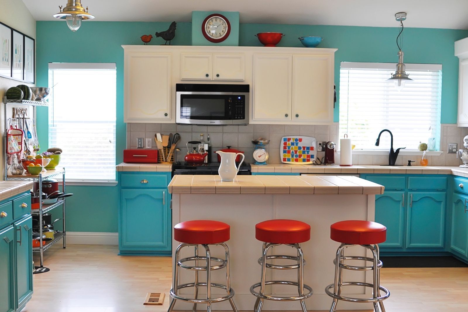 A kitchen with blue and white cabinets and red stools