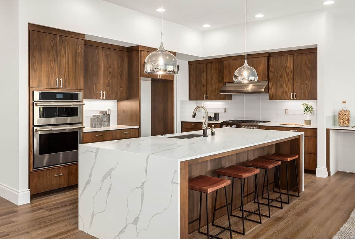 A kitchen with marble counter tops , wooden cabinets , and stainless steel appliances.